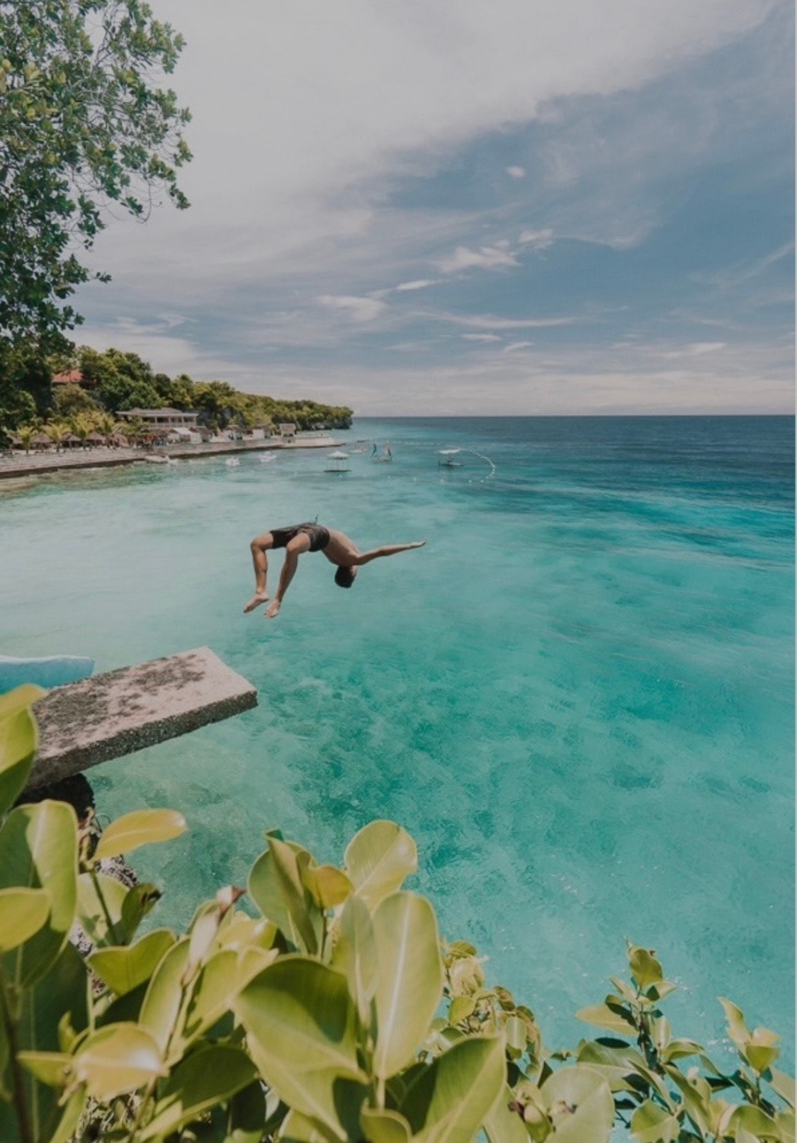 Cliff diver above clear water at Salagdoong Beach